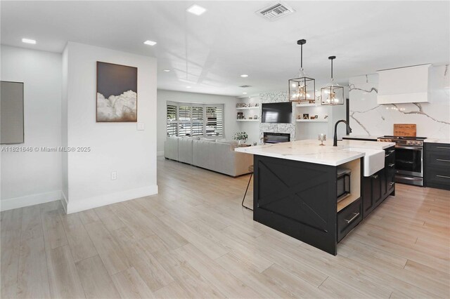 9627 SW 18th Ter, Miami, FL 33165 - kitchen with stainless steel stove, dark cabinets, a center island with sink, hanging light fixtures, and recessed lighting