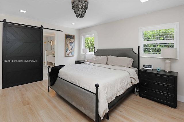 9627 SW 18th Ter, Miami, FL 33165 - bedroom with light wood-type flooring, a barn door, and connected bathroom