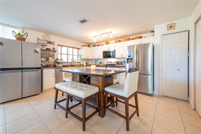15285 SW 30th Ter, Miami, FL 33185 - kitchen featuring appliances with stainless steel finishes, light tile patterned flooring, white cabinets, dark countertops, and a textured ceiling