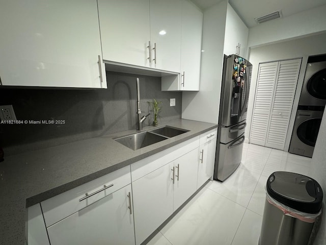 6315 SW 138th Ct Unit 6315-4, Miami, FL 33183 - kitchen with stainless steel fridge with ice dispenser, stacked washing machine and dryer, white cabinets, backsplash, and light tile patterned floors