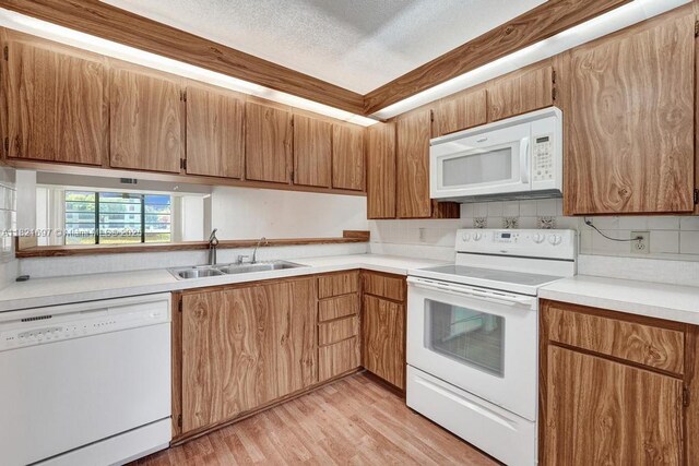 1520 Whitehall Dr Unit 103, Davie, FL 33324 - kitchen featuring white appliances, light countertops, light wood finished floors, brown cabinetry, and decorative backsplash