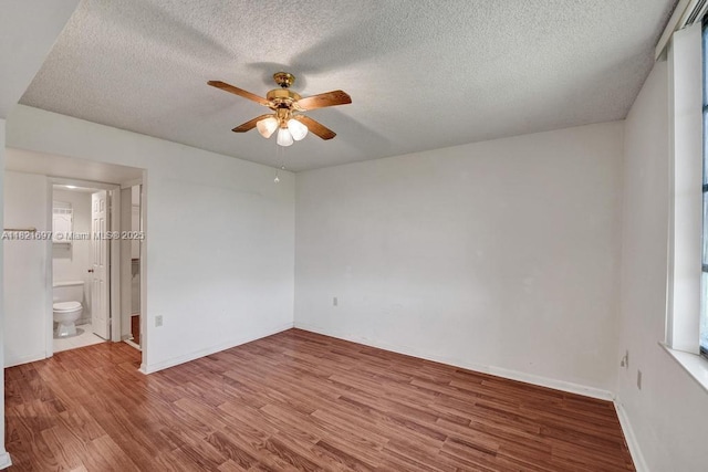 1520 Whitehall Dr Unit 103, Davie, FL 33324 - unfurnished bedroom featuring wood finished floors, a textured ceiling, ceiling fan, and ensuite bath