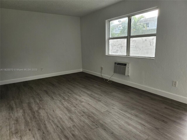 1239 Marseille Dr Unit 4, Miami Beach, FL 33141 - empty room with a wall mounted air conditioner, dark wood-type flooring, and a textured ceiling