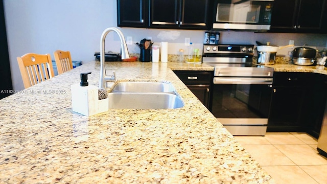 2190 SE 2nd St, Homestead, FL 33033 - kitchen with stainless steel appliances, dark cabinets, light stone counters, and light tile patterned floors