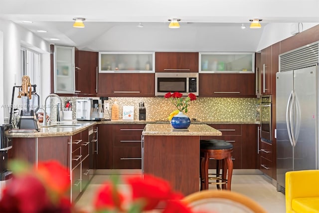 930 NE 182nd Ter, North Miami Beach, FL 33162 - kitchen featuring stainless steel appliances, a kitchen island, vaulted ceiling, tasteful backsplash, and modern cabinets