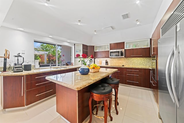 930 NE 182nd Ter, North Miami Beach, FL 33162 - kitchen with stainless steel appliances, a kitchen island, modern cabinets, decorative backsplash, and reddish brown cabinets