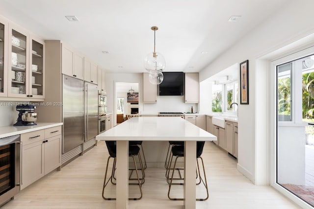 11100 Paradela St, Coral Gables, FL 33156 - kitchen featuring stainless steel built in refrigerator, beverage cooler, range hood, a breakfast bar area, and light wood-type flooring
