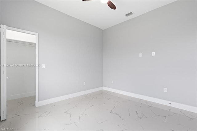 1003 Casino Ave, Lehigh Acres, FL 33971 - unfurnished bedroom featuring marble look tiles, a closet, ceiling fan, and a walk in closet