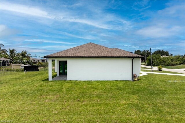 1003 Casino Ave, Lehigh Acres, FL 33971 - view of home's exterior featuring a yard, stucco siding, and a shingled roof