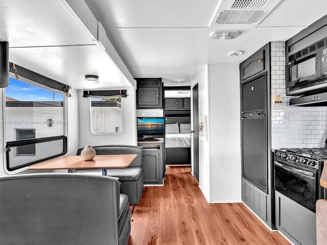 107 Central Ave, Delray Beach, FL 33483 - kitchen featuring black microwave, light wood-style floors, backsplash, and gas range