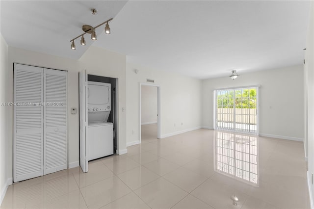 5271 SW 8th St Unit 213, Miami, FL 33134 - unfurnished living room with stacked washing machine and dryer, light tile patterned floors, and track lighting