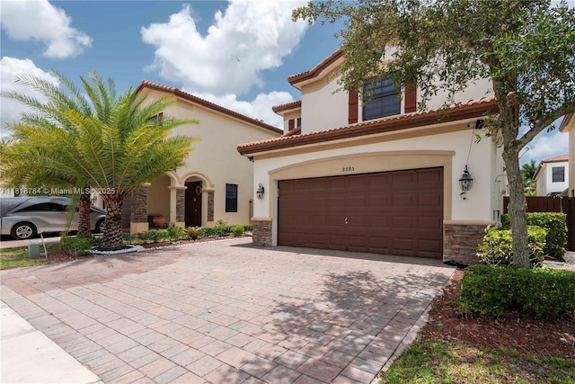 8885 NW 100th Pl, Doral, FL 33178 - mediterranean / spanish home featuring stone siding, an attached garage, stucco siding, and decorative driveway