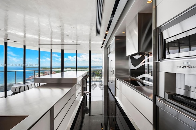 100 S Pointe Dr Unit 3003, Miami Beach, FL 33139 - kitchen featuring a water view, white cabinetry, dark tile patterned floors, expansive windows, and modern cabinets