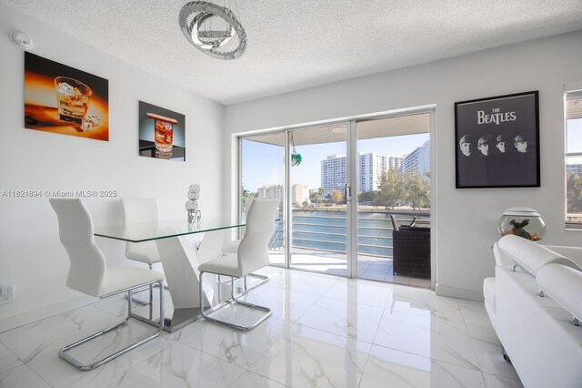 400 Diplomat Pkwy Unit 302, Hallandale Beach, FL 33009 - dining area with marble look tile flooring, healthy amount of natural light, a textured ceiling, and a water view