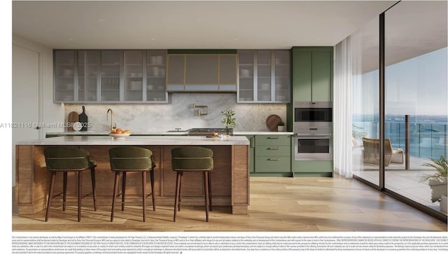 710 NE 29th St Unit 3901, Miami, FL 33137 - kitchen featuring green cabinetry, light wood-type flooring, decorative backsplash, light countertops, and a wall of windows