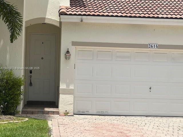 2614 SW 188th Ave, Miramar, FL 33029 - view of exterior entry featuring a tile roof, a garage, stucco siding, and decorative driveway