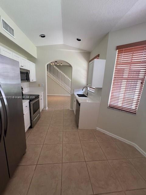 2614 SW 188th Ave, Miramar, FL 33029 - kitchen featuring appliances with stainless steel finishes, light tile patterned floors, white cabinetry, arched walkways, and light countertops