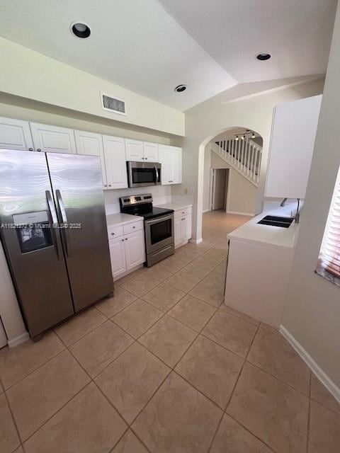 2614 SW 188th Ave, Miramar, FL 33029 - kitchen with appliances with stainless steel finishes, vaulted ceiling, light tile patterned floors, arched walkways, and white cabinets