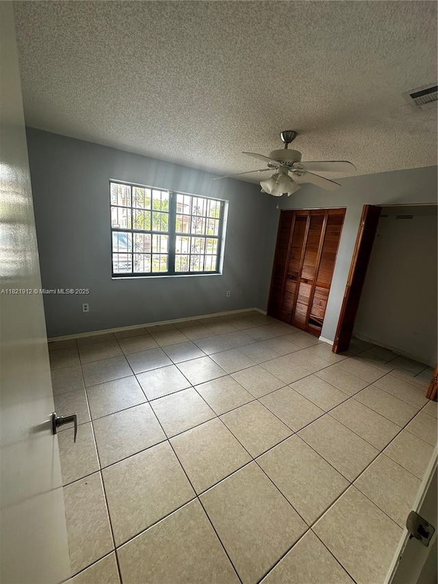 7535 W 5th Ct, Hialeah, FL 33014 - unfurnished bedroom with a textured ceiling, tile patterned floors, ceiling fan, and two closets