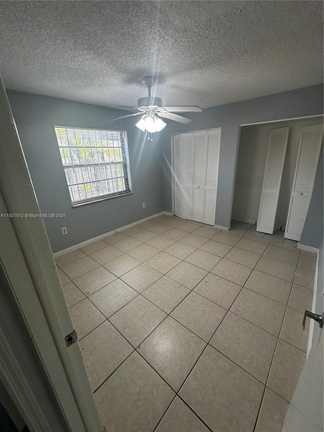 7535 W 5th Ct, Hialeah, FL 33014 - unfurnished bedroom with multiple closets, light tile patterned floors, a ceiling fan, and a textured ceiling