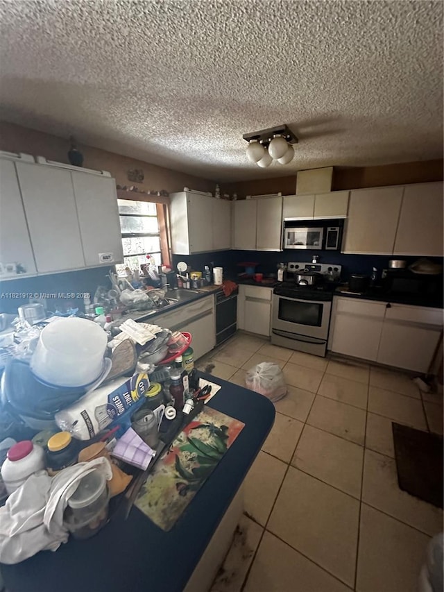 7535 W 5th Ct, Hialeah, FL 33014 - kitchen with appliances with stainless steel finishes, a textured ceiling, white cabinetry, dark countertops, and light tile patterned flooring