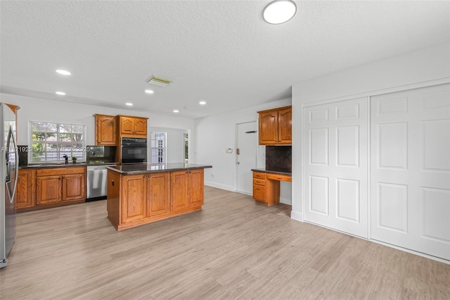 14821 SW 148th St Cir, Miami, FL 33196 - kitchen with a kitchen island, stainless steel appliances, light wood-type flooring, dark countertops, and brown cabinetry