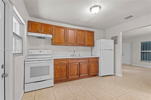 5288 N Andrews Ave, Oakland Park, FL 33309 - kitchen with white appliances, under cabinet range hood, brown cabinetry, light countertops, and light tile patterned floors