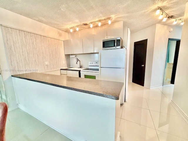 1936 S Ocean Dr Unit 7C, Hallandale Beach, FL 33009 - kitchen with white appliances, rail lighting, a peninsula, white cabinets, and a textured ceiling