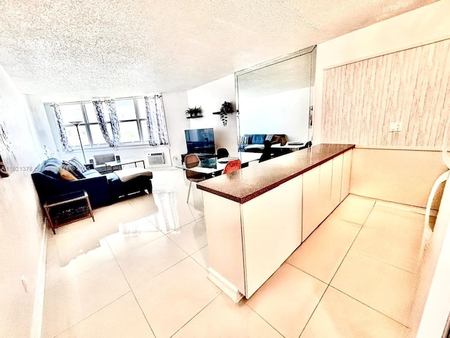 1936 S Ocean Dr Unit 7C, Hallandale Beach, FL 33009 - kitchen with open floor plan, a peninsula, light tile patterned floors, a textured ceiling, and white cabinetry
