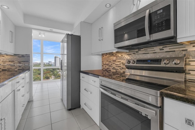 1901 Brickell Ave Unit B1508, Miami, FL 33129 - kitchen with stainless steel appliances, a wall of windows, backsplash, white cabinets, and light tile patterned floors