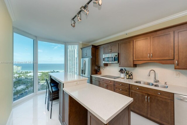300 S Pointe Dr Unit 1602, Miami Beach, FL 33139 - kitchen featuring stainless steel appliances, a center island, light countertops, and ornamental molding