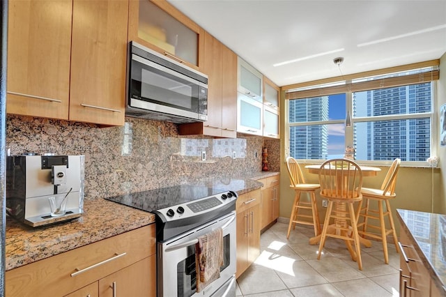 1833 S Ocean Dr Unit 1402, Hallandale Beach, FL 33009 - kitchen with appliances with stainless steel finishes, backsplash, light tile patterned floors, glass insert cabinets, and light stone counters