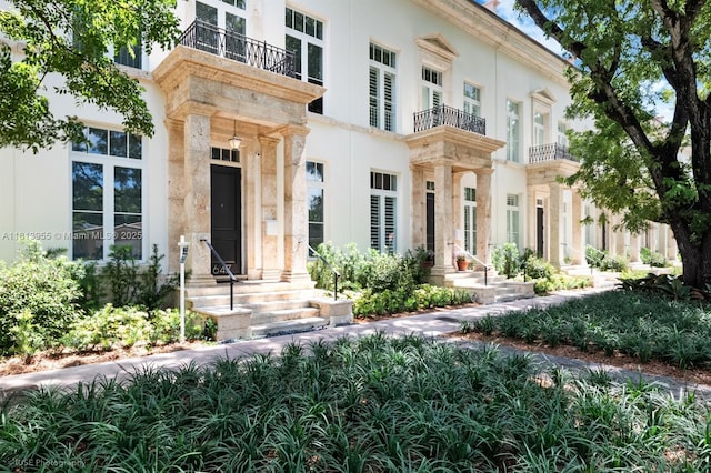 647 Almeria Ave, Coral Gables, FL 33134 - doorway to property featuring a balcony, stucco siding, and stone siding