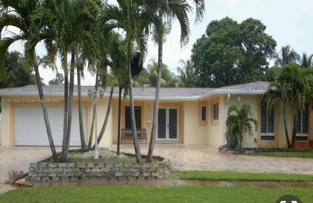 411 Martin Rd, Margate, FL 33068 - back of house featuring stucco siding, decorative driveway, a garage, and french doors