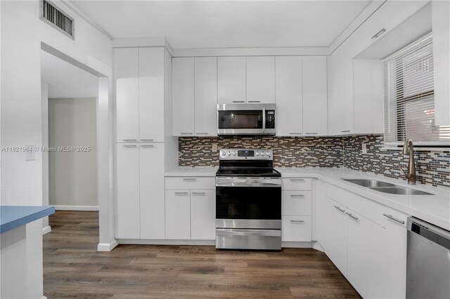 511 Ives Dairy Rd Unit 104-6, Miami, FL 33179 - kitchen featuring appliances with stainless steel finishes, decorative backsplash, dark wood-style flooring, and light countertops