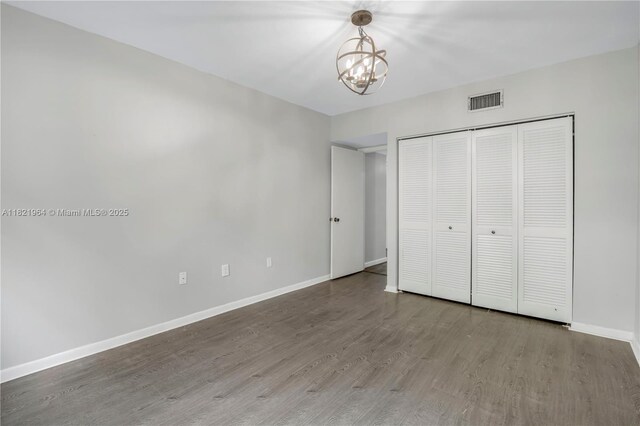 511 Ives Dairy Rd Unit 104-6, Miami, FL 33179 - unfurnished bedroom with wood finished floors, a chandelier, and a closet