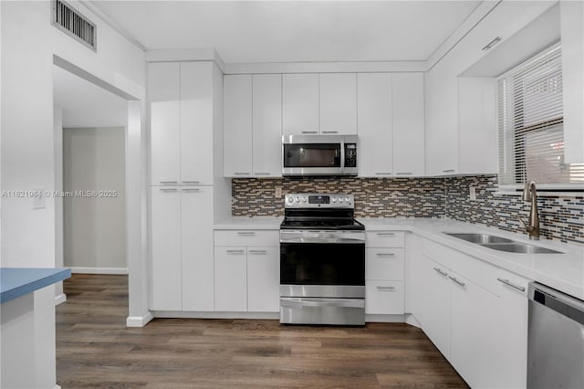 511 Ives Dairy Rd Unit 104-6, Miami, FL 33179 - kitchen featuring appliances with stainless steel finishes, decorative backsplash, dark wood-style flooring, and light countertops