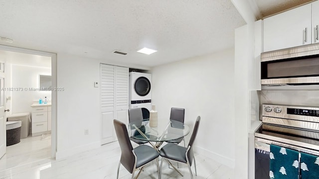 7180 NW 179th St Unit 105, Hialeah, FL 33015 - dining space featuring stacked washer / drying machine and a textured ceiling