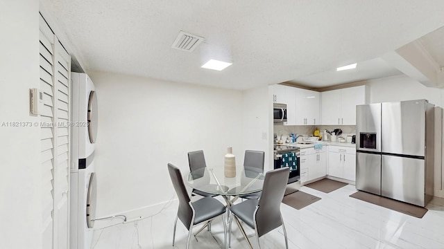 7180 NW 179th St Unit 105, Hialeah, FL 33015 - dining room featuring stacked washing machine and dryer and baseboards
