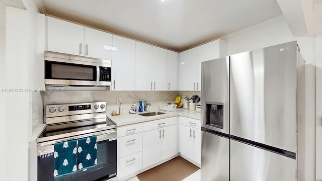 7180 NW 179th St Unit 105, Hialeah, FL 33015 - kitchen featuring stainless steel appliances, light countertops, tasteful backsplash, white cabinets, and ornamental molding