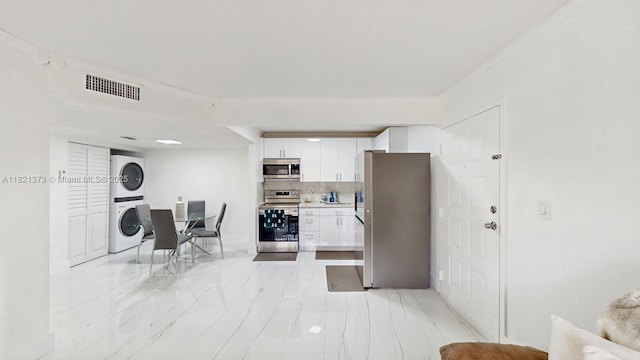 7180 NW 179th St Unit 105, Hialeah, FL 33015 - kitchen featuring stainless steel appliances, stacked washing machine and dryer, white cabinetry, light countertops, and light marble finish flooring