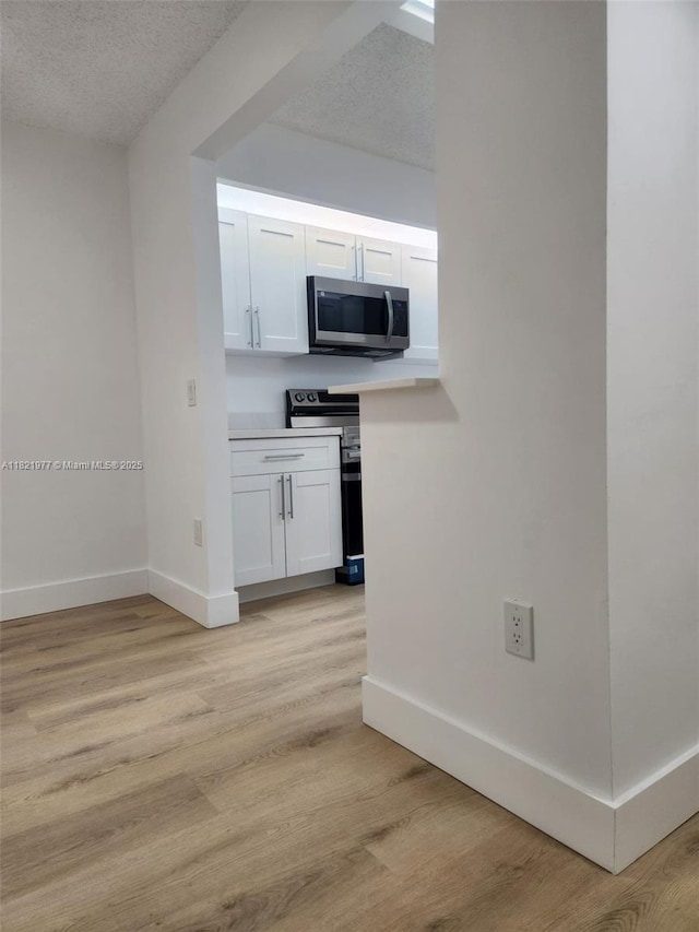 12755 SW 16th Ct Unit 201B, Pembroke Pines, FL 33027 - kitchen featuring appliances with stainless steel finishes, a textured ceiling, light wood finished floors, white cabinets, and light countertops