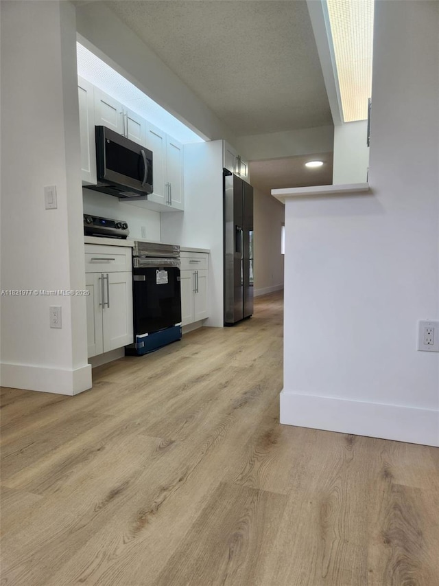 12755 SW 16th Ct Unit 201B, Pembroke Pines, FL 33027 - kitchen with appliances with stainless steel finishes, white cabinets, light wood-style floors, and light countertops