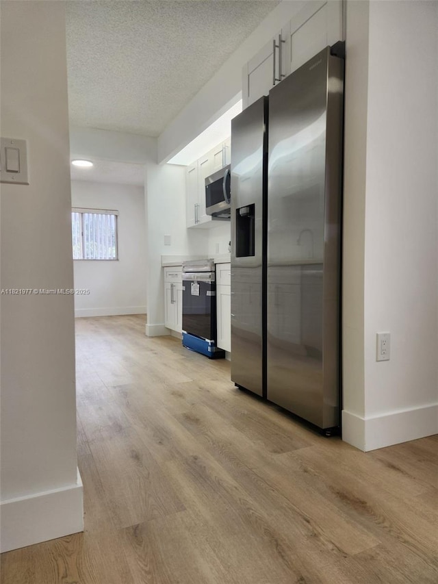 12755 SW 16th Ct Unit 201B, Pembroke Pines, FL 33027 - kitchen with stainless steel appliances, light wood-type flooring, white cabinetry, a textured ceiling, and light countertops