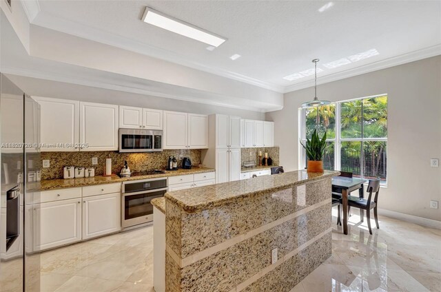 21235 NE 33rd Ave, Aventura, FL 33180 - kitchen with stainless steel appliances, ornamental molding, backsplash, white cabinetry, and light stone countertops