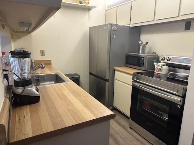 6447 Chasewood Dr Unit C, Jupiter, FL 33458 - kitchen with stainless steel appliances, butcher block counters, wood finished floors, and white cabinetry