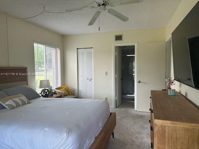 6447 Chasewood Dr Unit C, Jupiter, FL 33458 - bedroom with light carpet, a closet, ensuite bath, a textured ceiling, and ceiling fan