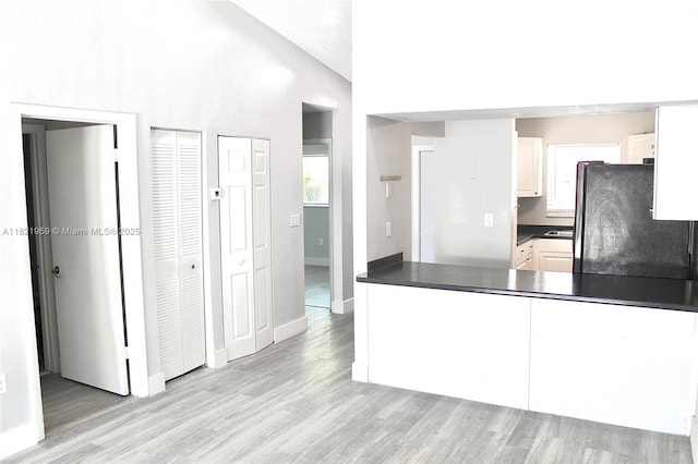 1061 SE 13th Ave Unit 1061, Homestead, FL 33035 - kitchen with freestanding refrigerator, dark countertops, light wood-style floors, a peninsula, and white cabinets