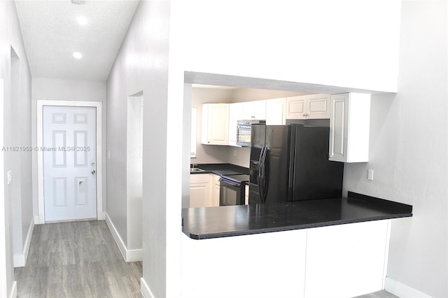 1061 SE 13th Ave Unit 1061, Homestead, FL 33035 - kitchen with black appliances, dark countertops, light wood-type flooring, white cabinetry, and a peninsula