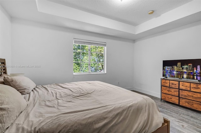 8940 NE 8th Ave Unit 1203, Miami, FL 33138 - bedroom featuring a tray ceiling, wood finished floors, and a textured ceiling